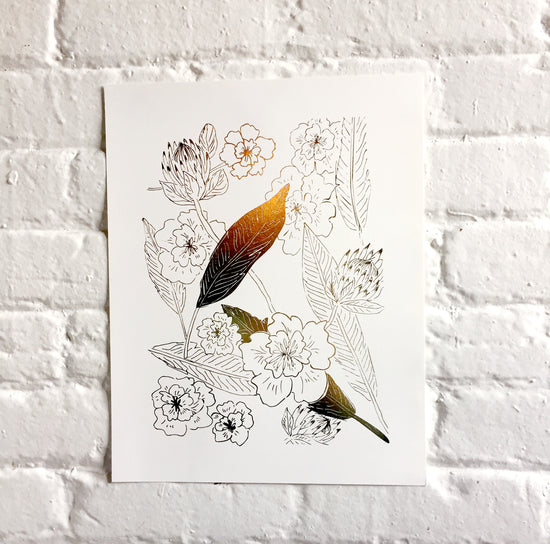 Photo of a Botanical art print with floral pattern in gold foil against a white brick wall