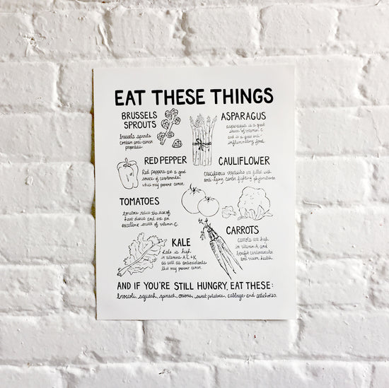 Art print entitled "Eat These Things" with illustrations of brussels sprouts, asparagus, red pepper, cauliflower, tomatoes, kale, and carrots. Also includes their health benefits.